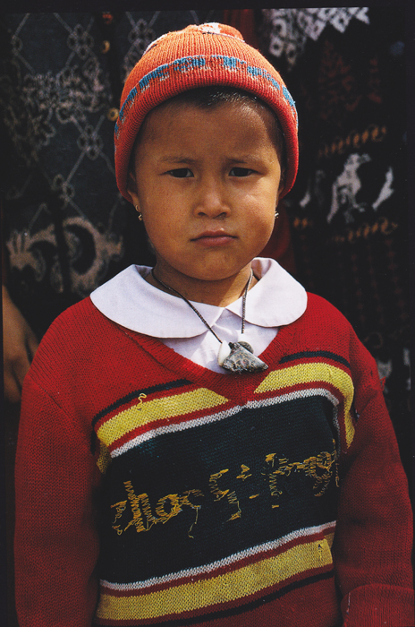 child wearing hat, sweater and amulet necklace
